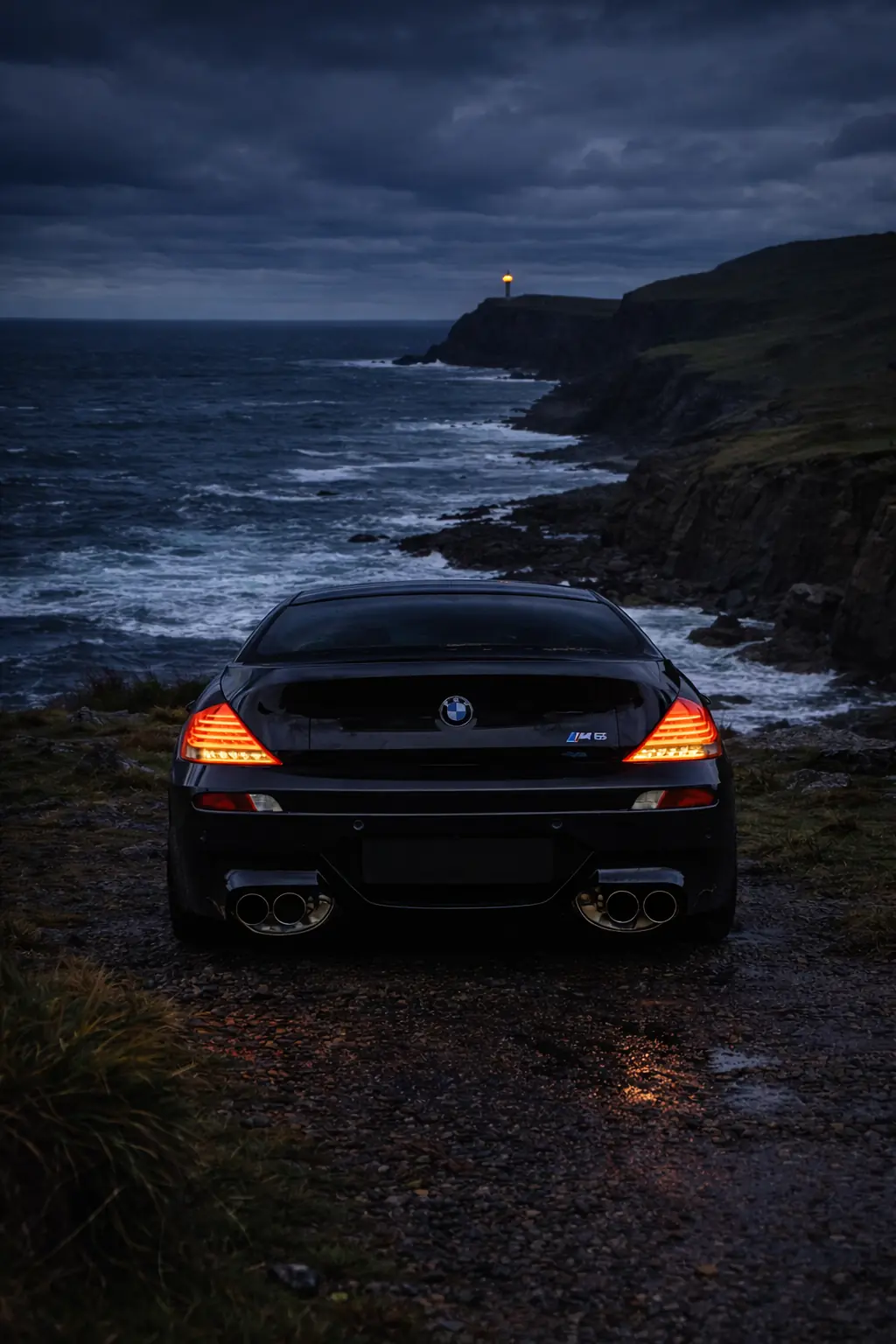 BMW M6 on a cliff top at night facing a lighthouse